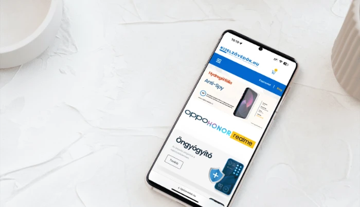 Chytrý telefon na stole zobrazující maďarský e-shop Kijelzővédők.hu